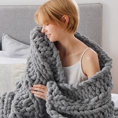 a woman wrapped up in a gray blanket