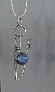 An abstract sterling silver pendant, approximately 1.5 inches long, highlights a glorious mid-blue kyanite cabochon.  Simple, abstract, not traditional, this necklace looks amazing against bare skin, but also with a sweater or even a t-shirt.  Versatile, celebratory, fun! Abstract Silver Jewelry, Silver Kyanite Jewelry As Gift, Silver Kyanite Jewelry For Gift, Kyanite Necklace, Rock Rings, Simple Abstract, Wifi Signal, Bare Skin, Blue Kyanite