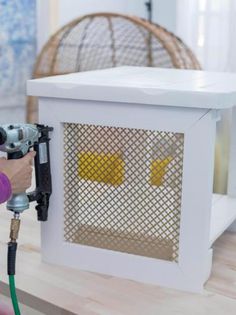 a person using a power drill to paint a white box