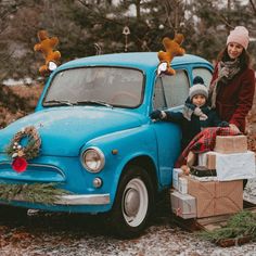 a woman standing next to a blue car with christmas decorations on it