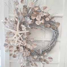 a wreath with silver leaves and starfishs hanging on the front door to welcome guests