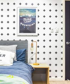 a bedroom with black and white crosses on the wall next to a bed, lamp and door