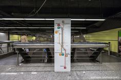 there is a large sign on the floor in front of some benches and tables with people standing around it