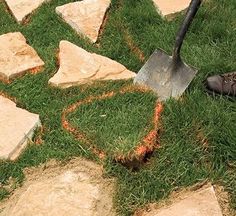 a shovel is laying on the grass next to some rocks and stones that have been cut into squares