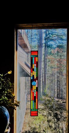 a stained glass window with trees in the back ground and bushes on the other side