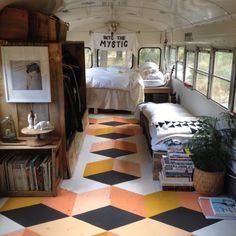 the inside of an old school bus is decorated with colorful floor tiles and bookshelves