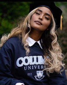 a young woman wearing a graduation cap and gown sitting on a bench with her eyes closed