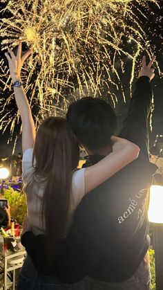 a man and woman embracing in front of fireworks