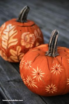 two orange painted pumpkins sitting on top of a wooden table next to each other