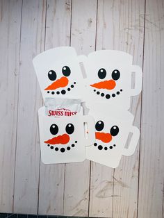 four snowman mugs sitting on top of a wooden table