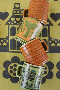 four coffee mugs stacked on top of each other in front of a wallpaper