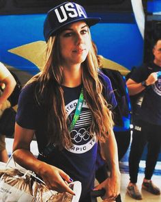 a woman in a usa t - shirt and hat carrying luggage