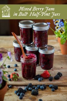 mixed berry jam in half - pint jars on a wooden table with fresh berries