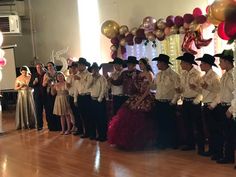 a group of people standing next to each other on a wooden floor in front of balloons