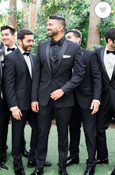 a group of men in tuxedos standing next to each other on the grass