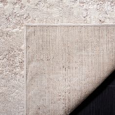 an area rug on the ground next to a black and white wall with a piece of cloth