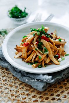 a white plate topped with pasta covered in sauce and veggies next to a fork