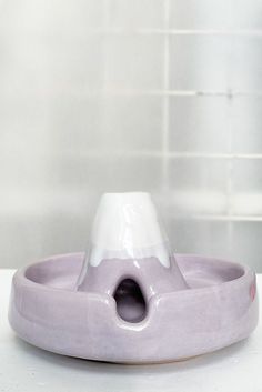 a purple and white ceramic dish with a hole in the center on a counter top