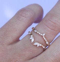 a woman's hand with two rings on it, one is gold and the other is white