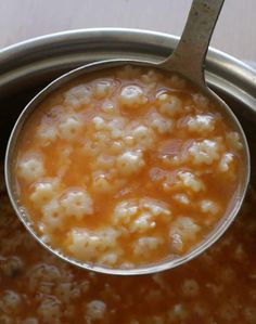 a ladle filled with food sitting on top of a metal pan covered in liquid