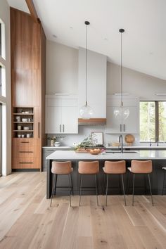 a large kitchen with wooden floors and white cabinetry on the walls, along with four chairs