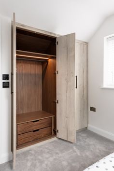 an empty bedroom with a wooden closet in the corner and two drawers on each side