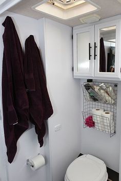 a white toilet sitting in a bathroom next to a mirror and towel rack on the wall