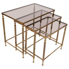 a set of three glass and brass nesting tables