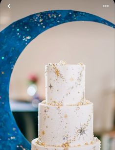 a three tiered white cake with gold sprinkles