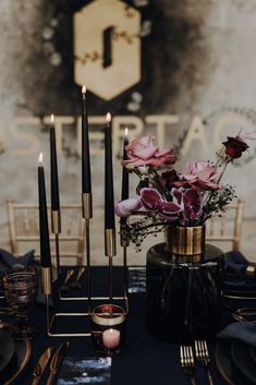 a table topped with candles and flowers on top of a black table cloth covered table