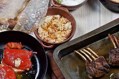 several different types of food are being prepared in pans on a table with utensils