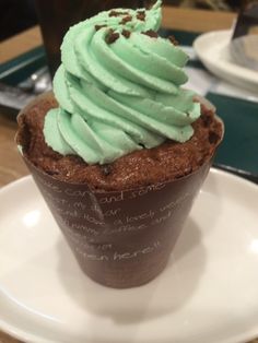 a chocolate cupcake with green frosting on a white plate