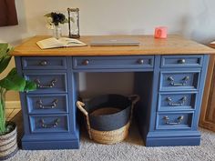 a blue desk with an open book on top and a basket under the desk next to it