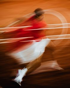 a blurry photo of a man running in the street with a red shirt and white skirt