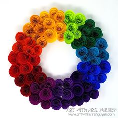 there are many different colors of rolled paper flowers in the shape of a rainbow ring