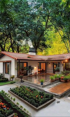 a house with an orange tiled roof surrounded by greenery and potted plants in the front yard