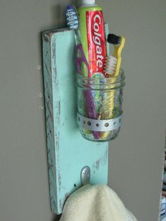 a toothbrush holder is hanging on the wall with toothpaste and tooth brushes in it