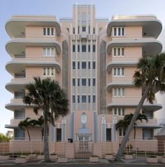 an apartment building with palm trees in front of it