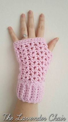 a woman's hand wearing a pink crochet wrist warmer