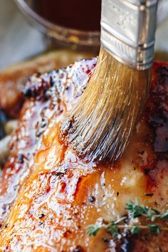 a brush is being used to brush the top of a piece of meat with sauce