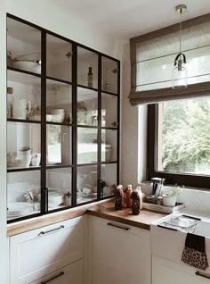 a kitchen filled with lots of white dishes and cupboards next to a large window