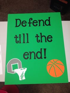 a green sign that says defend till the end with basketballs and hoop on it