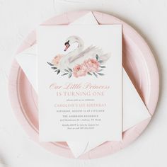 a pink and white swan birthday party with flowers on it's head, sitting on a plate