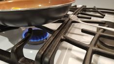 a frying pan is on the burner of a gas stove with an electric flame