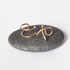 a gold ring sitting on top of a rock next to a black stone with the letter e in it