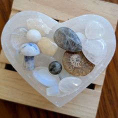 a heart shaped box filled with rocks and stones on top of a wooden table,