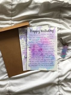 a birthday card sitting on top of a bed next to an envelope with the message happy birthday