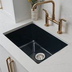 a kitchen sink with two faucets on the side and a gold faucet