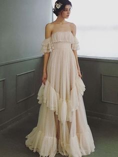 a woman standing in front of a window wearing a dress with ruffles on it