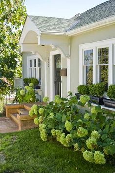 a white house with green plants in the front yard